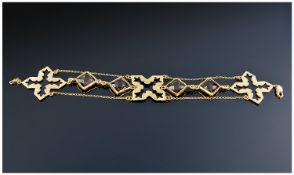 A Silver Gilt and Smokey Quartz Bracelet. Three silver cross shapes between parallel chains and