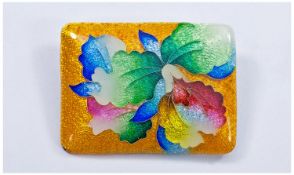 A Japanese Enamelled Brooch. Rectangular in shape. Enamelled with an Iris Flowerhead in red,