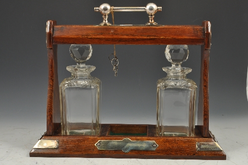 Oak tantalus, electroplated mounts, fitted with two (of three) spirit decanters, width 38cms.