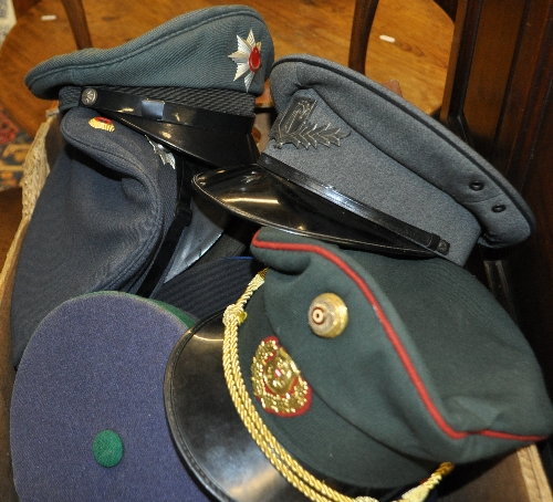 Collection of German and other Continental peaked caps, some with metal, some with plastic badges.