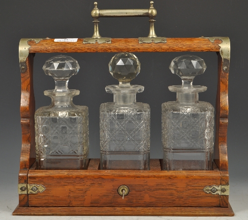 Edwardian oak tantalus, plated mounts with three cut-glass spirit decanters, width 35cms.