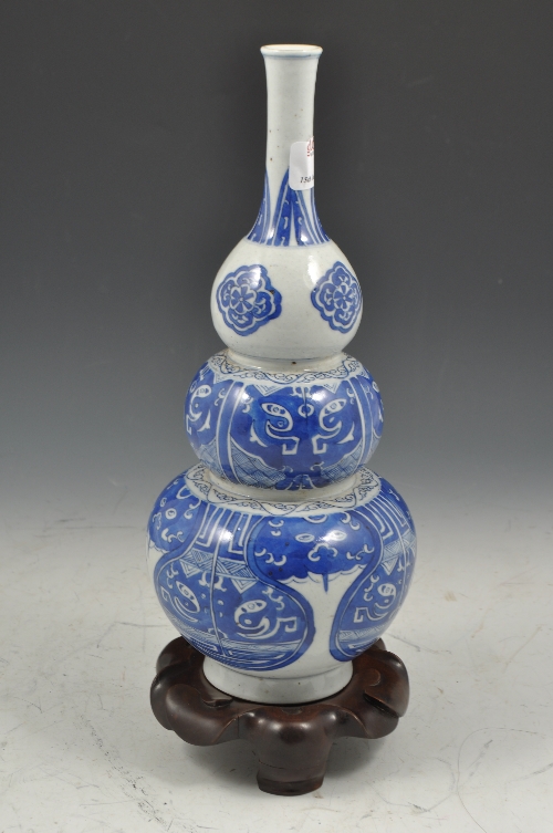 Chinese blue and white triple gourd vase, stylised decoration on a hardwood stand, 33cms overall.