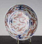 A Chinese underglaze blue and iron red `dragon` saucer dish, early Kangxi period, the underside with