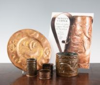 A small collection of Newlyn copper ware items, including a cylindrical pot with embossed fish