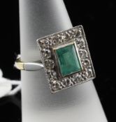 An 18ct gold, emerald and diamond cluster tablet ring, the rectangular emerald bordered by