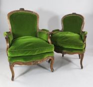 A near pair of Victorian walnut bergeres, with floral carved show wood frames and green velvet