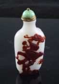 A Chinese white and ruby glass overlaid snuff bottle, moulded in relief with a bird in a pine tree