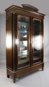 A Charles X brass mounted mahogany vitrine, with arched pediment and two bevelled glazed doors