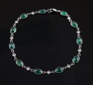 An 18ct white gold, emerald and diamond bracelet, set with eleven oval cut emeralds with an