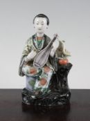 A Chinese famille verte biscuit glazed figure of a seated lady musician, early 18th century, holding