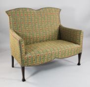 An Edwardian mahogany two seater settee, upholstered with floral striped fabric, on swept squared