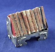 An Edwardian Art Nouveau silver miniature book rack, with stylised scroll borders, George