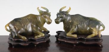 A pair of Chinese green and russet bowenite figures of recumbent oxen, 5.75in. (14.5cm), wood