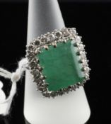 A white gold, emerald and diamond set dress ring, the large rectangular cut emerald bordered by