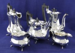 A George V silver five piece tea set, of shaped oval baluster form, with ebonised handles, on