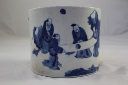 A Chinese blue and white brushpot, in Kangxi style, painted with scholars examining a scroll amid