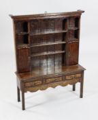 An Edwardian miniature oak Welsh dresser, with rack, cupboards and three drawers, on squared legs,