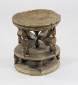 A Dogon carved hardwood stool, decorated with elongated masks, 1ft 3.5in.