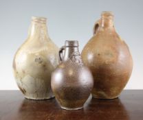Three salt glazed stoneware bellarmines, 17th century, two with masks, one with mottled glaze, 7.5 -