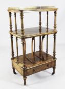 A Victorian figured walnut Canterbury whatnot, with three shelves and base drawer, on brass castors,