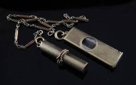 A 9ct gold mounted cigar cutter and a 9ct gold cylindrical pill box suspended on a 9ct gold chain,