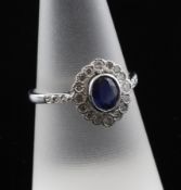An 18ct white gold, sapphire and diamond cluster ring, of oval form, with diamond set shoulders,