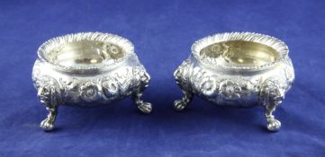 A pair of Victorian silver bun salts, with embossed floral decoration, lion mask knees, on claw