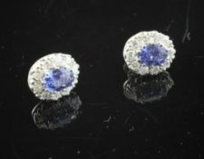 A pair of 18ct white gold, sapphire and diamond cluster earrings, of oval form.