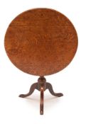 A George III oak tripod table, c.1760, the circular four plank tilt-top on a baluster stem with