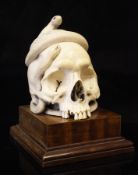 A large Japanese ivory okimono of a human skull with entwining snakes, Meiji period,