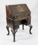 A mid 18th century walnut bureau, the fall enclosing pigeon holes, central cupboard and well over
