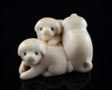 A Japanese ivory netsuke of three puppies, late 19th / early 20th century, with horn inset eyes, 1.