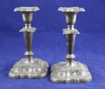 A pair of Edwardian silver dwarf candlesticks, with tapering stems and foliate scroll repousse