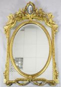 A 19th century French giltwood wall mirror, with Sevres style porcelain plaque inset to the pediment