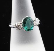 An 18ct white gold, three stone emerald and diamond ring, the 1.70ct oval cut emerald flanked by