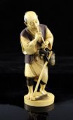 A fine Japanese ivory figure of a farmer smoking a tobacco pipe, Taisho period, with brown stained