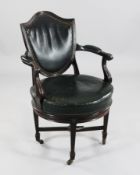 A late Victorian mahogany revolving desk chair, with shield shape back and green leather upholstery,