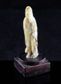 A small Chinese celadon and brown jade figure of an immortal, Han dynasty or later, with flowing