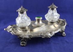 A Victorian silver inkstand, of shaped oval form, with foliate scroll border and scroll feet, with