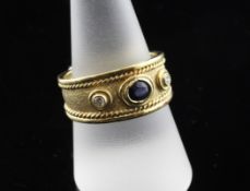 An 18ct gold, three stone sapphire and diamond set ring, with textured shank and rope twist