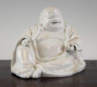 A Chinese Dehua blanc de chine seated figure of Budai, 17th/18th century, holding a ball in his left