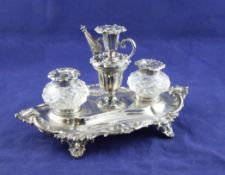 A Victorian silver desk stand, of lozenge shape with shell and scroll border, two mounted wells