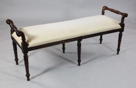 An Edwardian mahogany window seat, with turned and foliate carved arms and matching tapered legs,