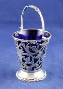 An Edwardian pierced silver sugar basket, of tapering form, with scroll decoration and blue glass