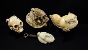 Three Japanese ivory netsuke, c.1940. the first carved as a skull with a snake crawling through