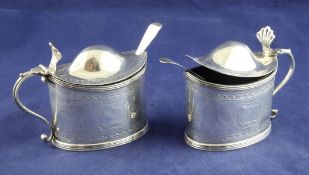 A pair of Edwardian 18th century style silver mustard pots, of oval form, with engraved borders,