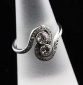 A 1920`s platinum and two stone diamond crossover ring, with scrolling diamond set border, size L..