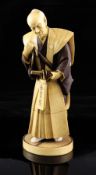 A fine Japanese stained ivory figure of a samurai, Taisho period, the figure in standing pose with