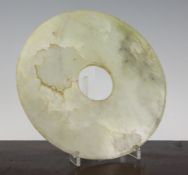 A large Chinese bowenite bi disc, the stone a pale green tone with white and russet inclusions, 8.