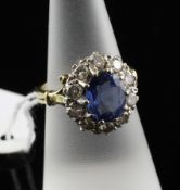 An 18ct gold, sapphire and diamond cluster dress ring, the oval cut sapphire bordered by ten round